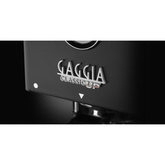 Close-up of the silver Gaggia Classic UP badge on the black espresso machine.
