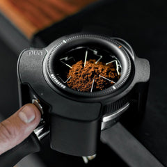 Puq Navigator WDT tool on portafilter with coffee grounds & finger touching the button
