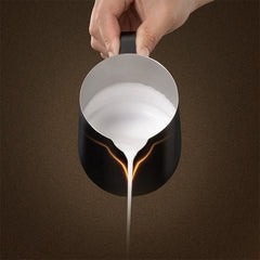 Hand pouring milk with black Timemore Rosetta Pro Milk Pitcher