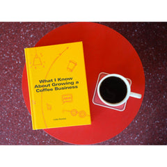 What I Know About Growing a Coffee Business by Colin Harmon beside a cup of black coffee on a red table.