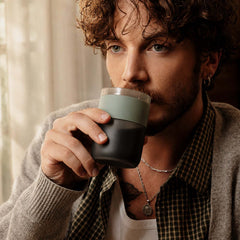 Person drinking coffee from the Wacaco Prestina cup with its Sage Green grip.