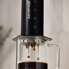 Close-up of coffee dripping from the AeroPress Stainless Steel Coffee Press into a glass mug.