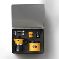 Open Bialetti x The North Face case with moka pot, two cups, two spoons and yellow coffee tin in fitted inserts.