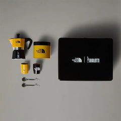 Overhead view of the Bialetti x The North Face moka pot, coffee tin, two cups and two spoons beside the black case.