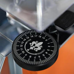 Eureka Mignon King Size Dial installed on an orange coffee grinder, showing numbered settings and fine-to-coarse arrows.