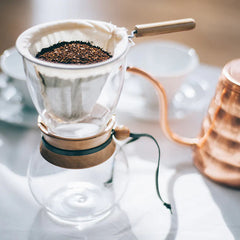 Hario Drip Pot Woodneck coffee brewer with fresh coffee grounds and goose neck kettle