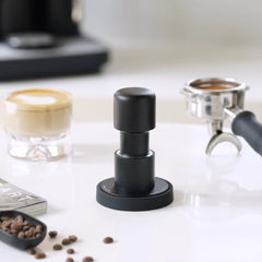 Timemore Impulse Impact spring loaded tamper on a bar with portafilter and coffee beans