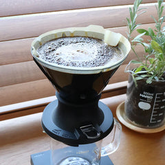 Hario Mugen Switch dripper in use on a bar with coffee immersed in water