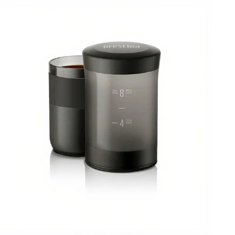 Wacaco Prestina portable coffee maker beside its coffee-filled cup.