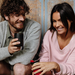 Two people smiling with coffee cups, one holding the Wacaco Prestina cup.